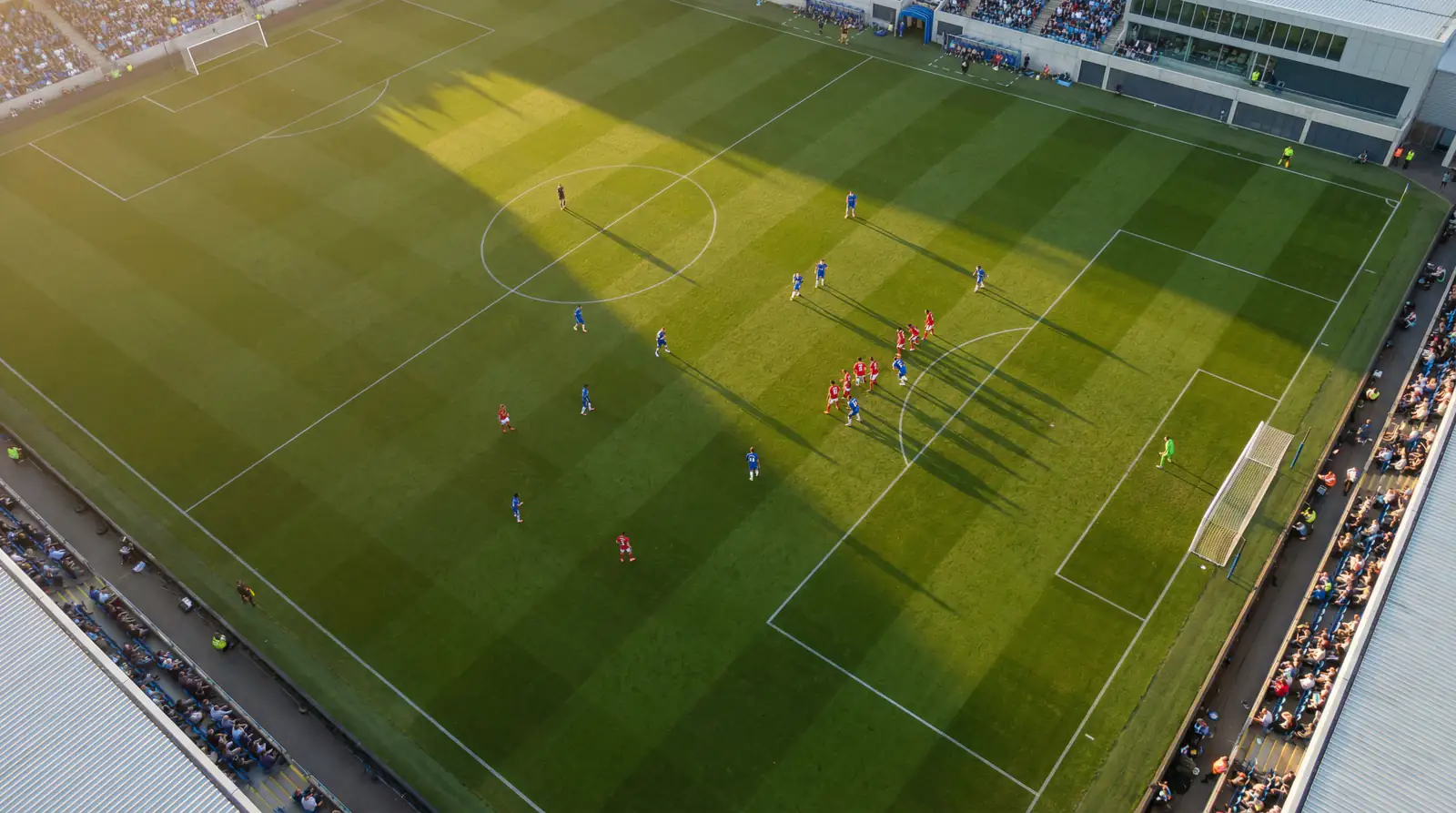 Vista aérea de un campo de fútbol mostrando formaciones tácticas de ambos equipos